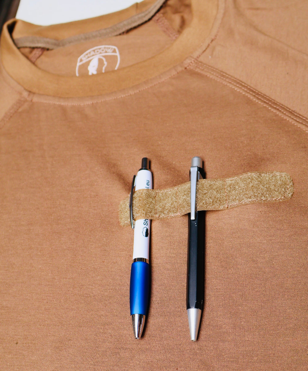 Two pens attached to a brown shirt with security patch velcro tape.
