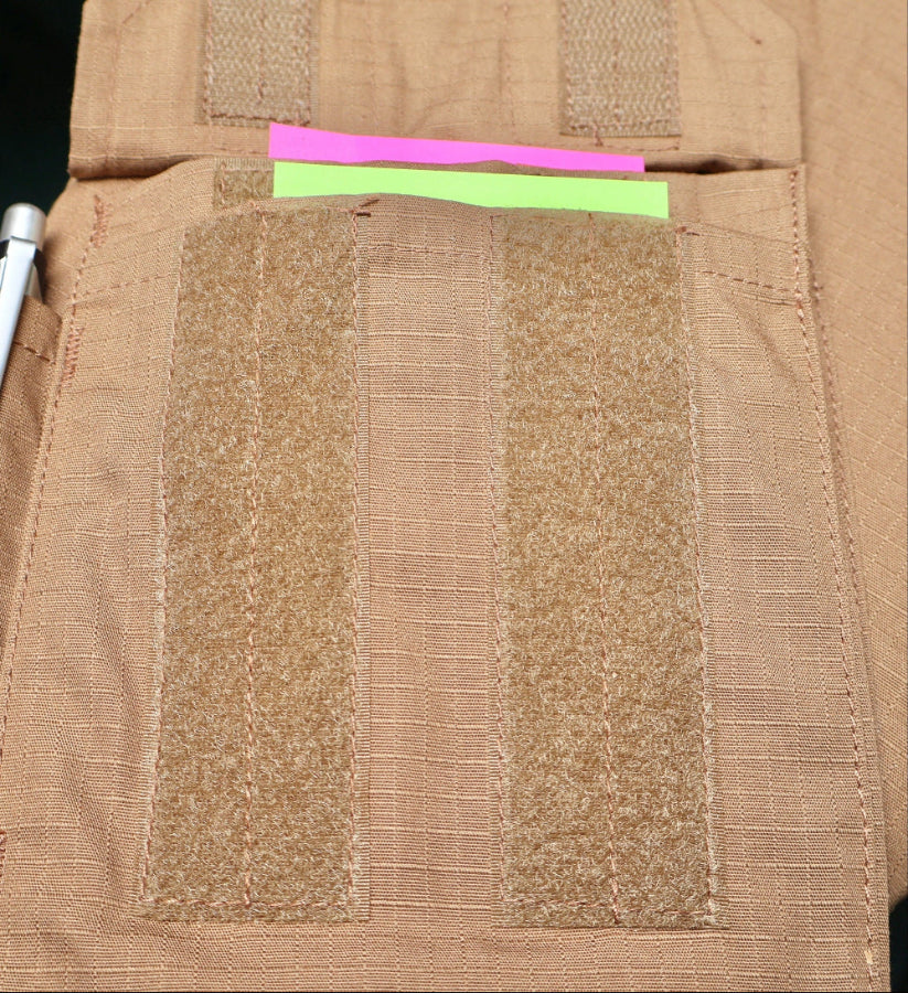 Close-up of a Coyote brown Combat tactical Shirt with multi pocket and fabric patches and a pink and green strip by Shadow Strategic.