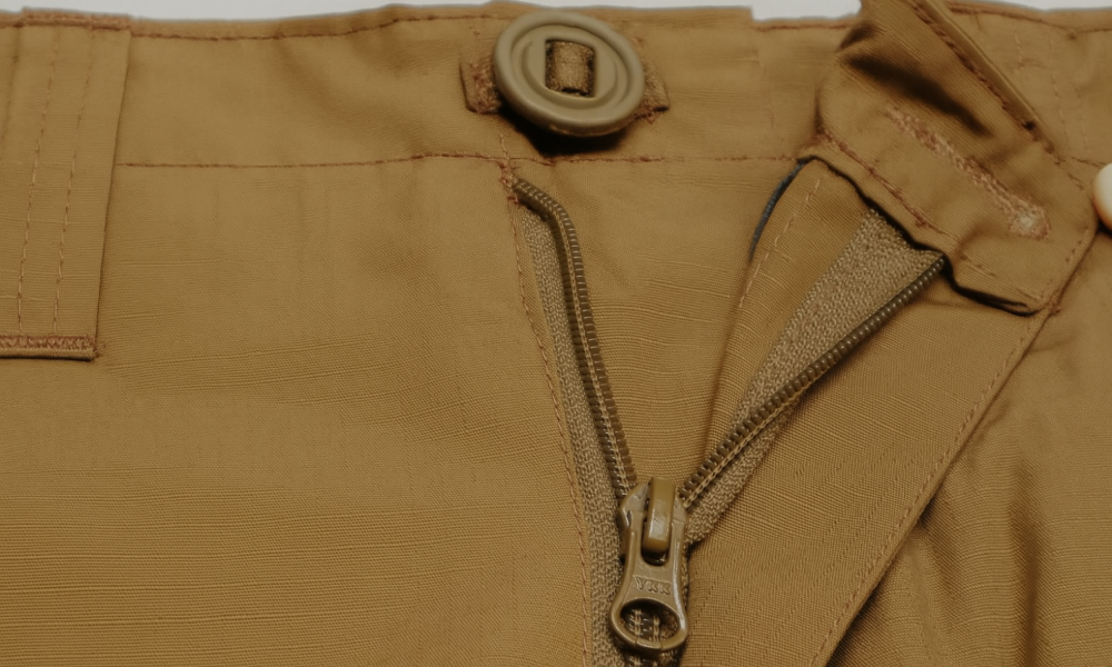 Close-up of a brown jacket with a YKK  zipper and button detail.
